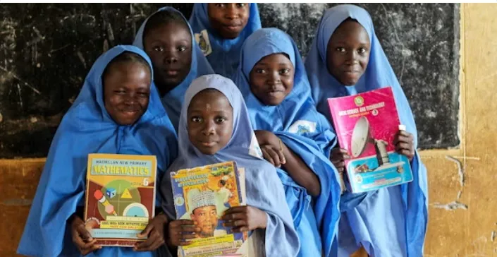 Pupils holding textbooks at a library outreach session in Ghana